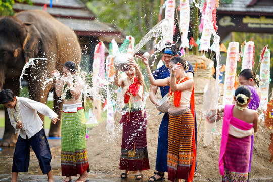 Group of Thai women and children ware Thai traditional dress play to splashing water on the Thai New Year's Day or Songkran festival in a fun way on elephant and pile of sand background.