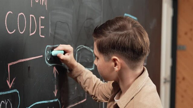 Closeup of smart student or boy writing prompt on blackboard. Child plan project and setting engineering system and brainstorm creative idea wrote on blackboard. Focus on hand. Site view. Erudition.