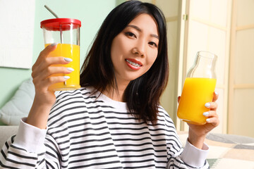 Beautiful Asian woman with glasses of juice at home, closeup