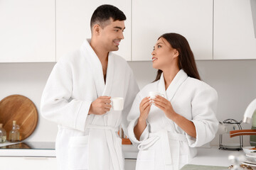 Obraz premium Happy young couple drinking coffee in kitchen