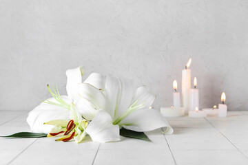 Beautiful lily flowers with burning candles on table