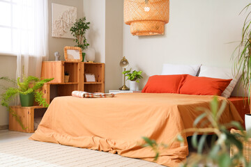 Interior of bedroom with green plants, bed and shelf unit
