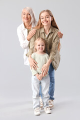 Little girl with her mom and grandmother on light background