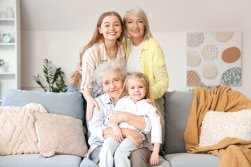 Fototapeta premium Little girl with her family sitting on sofa at home