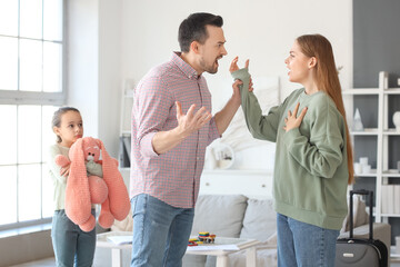 Sad little girl with toy and her arguing parents at home