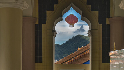 A red Chinese lantern is suspended in the opening of a window with an elegant arched vault against...