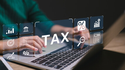 A person is typing on a laptop with a screen that says Tax