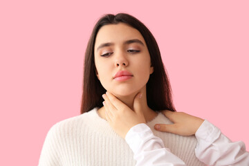 Endocrinologist examining thyroid gland of young woman on pink background