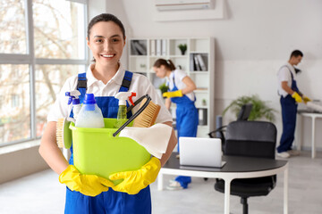 Female janitor with bucket of cleaning supplies in office