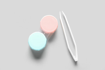 Container for contact lenses with tweezers on white background