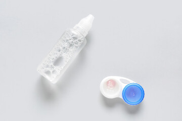 Container with contact lenses and solution on white background