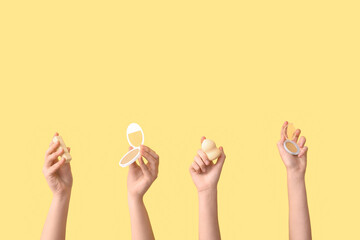 Female hands with sponge, lipstick and powder on yellow background