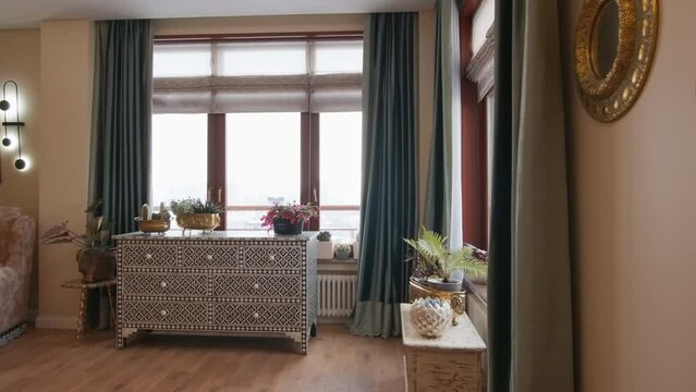 Cozy interior of a new apartment in beige and brown colors. Creative. Armchair and drawer by the window.