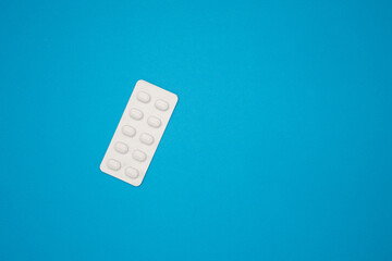 Pills in the blister pack are isolated on a blue background with copy space.