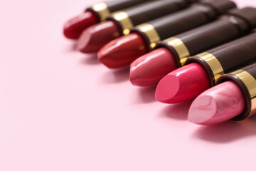 Different lipsticks on pink background, closeup