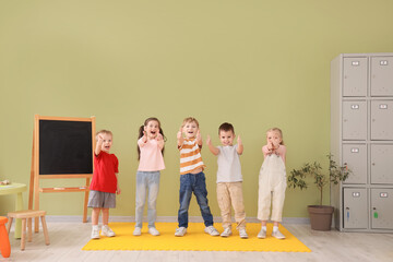 Little children showing thumbs-up in kindergarten