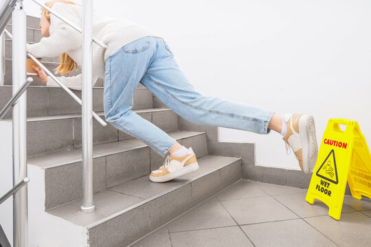Young woman falling down on wet steps in stairway. Trauma concept