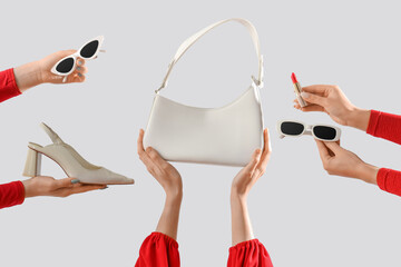 Female hands with stylish women's bag, sunglasses and high heels on grey background