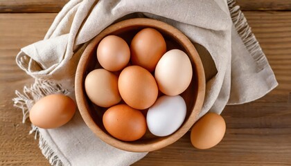 Chicken eggs of different brown and beige shades in a large wooden bowl on a wooden table  - 757711844