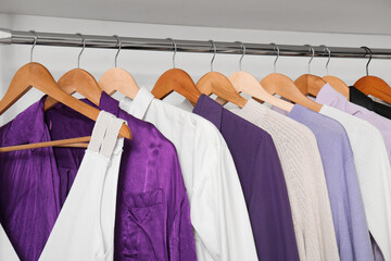Rack with clothes in purple and white shades in modern woman's wardrobe