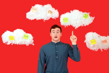 Young man pointing at clouds with reminders on red background