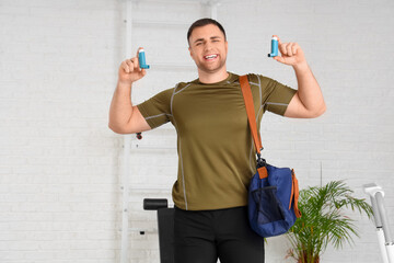 Sporty young man with bag and inhalers in gym