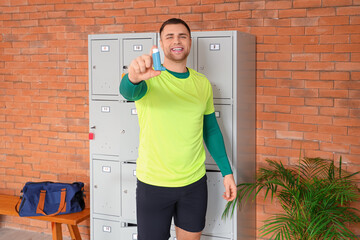 Sporty young man with inhaler near locker in gym