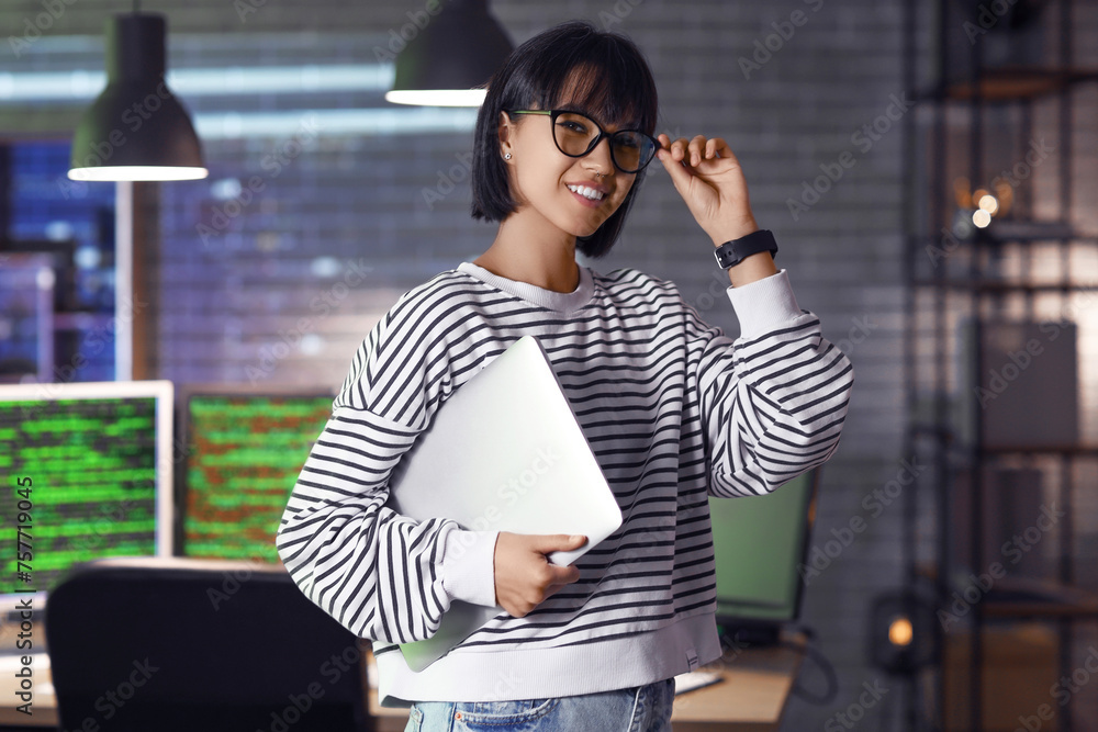 Canvas Prints Smiling female programmer with laptop in office at night