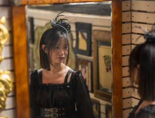 A lady in black dress in front of mirror.