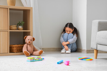 Lonely little Asian girl with autistic disorder sitting in corner at home