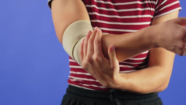 cropped woman wearing elastic support elbow brace for reduce pain, blue background, copy space