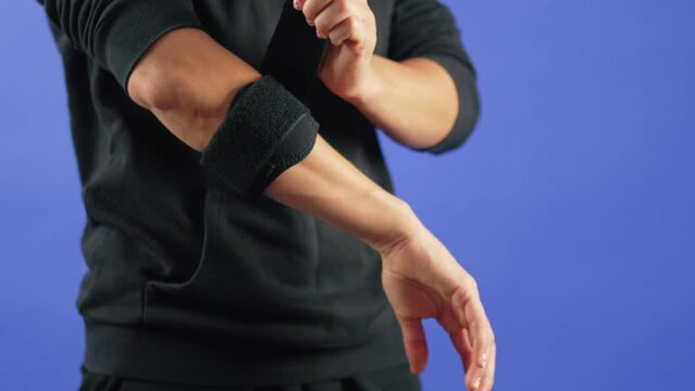 a person applying an elbow brace on an injured hand, blue background