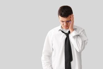 Tired young businessman on light background