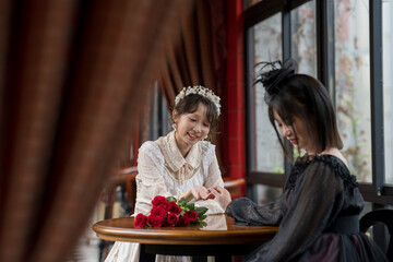 A woman in white and a woman in black sit together and chat.