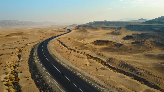 Empty asphalt road winding through a vast desert landscape, symbolizing adventure and exploration