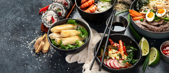 Traditional Asian food table. Spring roll, rice, shrimp, sushi, vegetables, meat on dark background