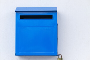 Close-up blue color iron mailbox on square shape that installed on white concrete wall for receive newspaper, letter, document and other from postman or company messenger