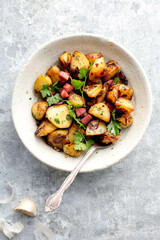 Sautéed potatoes with garlic and parsley, presented in an organic dish on a light background.