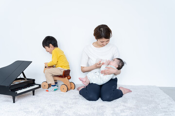 子供に哺乳瓶でミルクをあげる女性