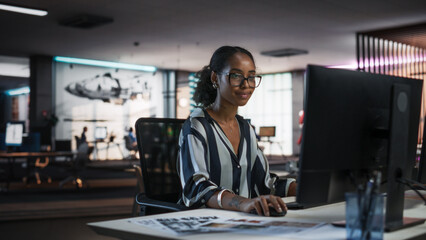Young Black Woman Working on Desktop Computer in Creative Office. Multiethnic Marketing Manager Writing Email Messages, Developing Social Media Strategy, and Researching Project Plan Details Online - obrazy, fototapety, plakaty