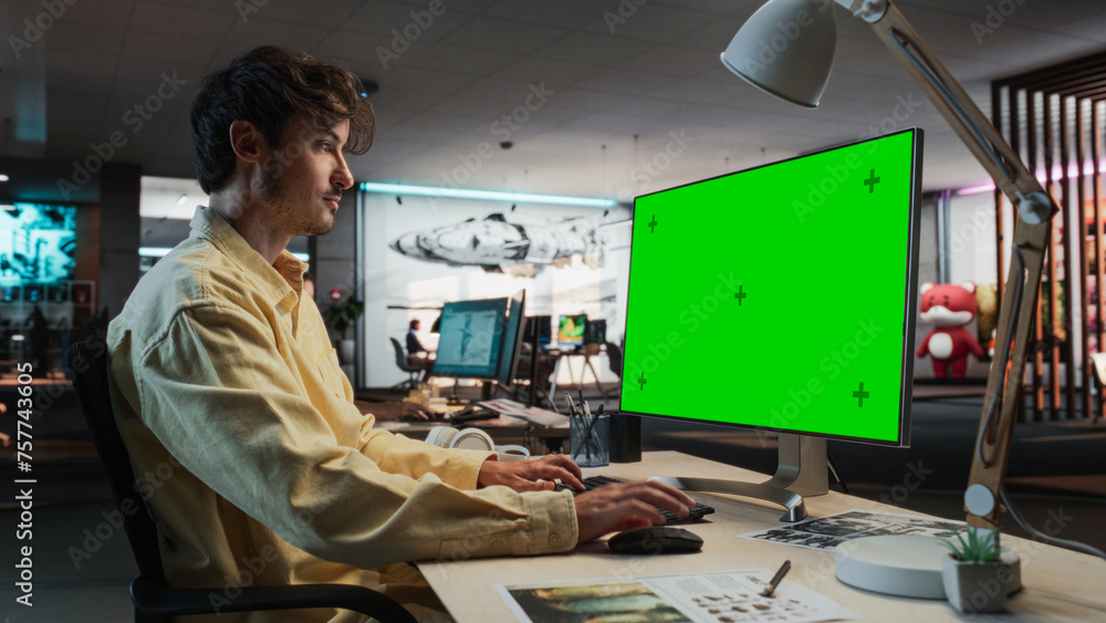Poster Caucasian Man Using Desktop Computer with Mock-up Green Screen Chromakey. Male Concept Artist Working in Game Design Startup Diverse Office, Creating Immersive Gameplay For New Survival Video Game.