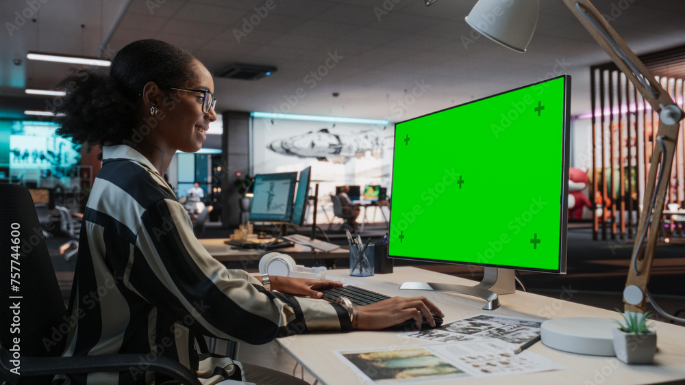 Aufkleber Portrait of Creative Black Female Sitting at a Desk Using Desktop Computer with Mock-up Green Screen. Female Concept Artist Working in Game Design Startup Office, Creating Immersive Gameplay.