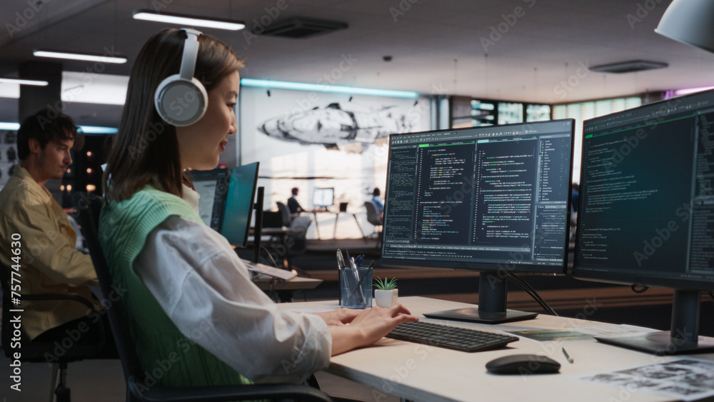 Aufkleber Female Asian Game Programmer Coding On Desktop Computer In Game Development Studio Diverse Office. Focused Woman Writes Lines Of Code, Does Gameplay Engineering For New Immersive 3D RPG Video Game.
