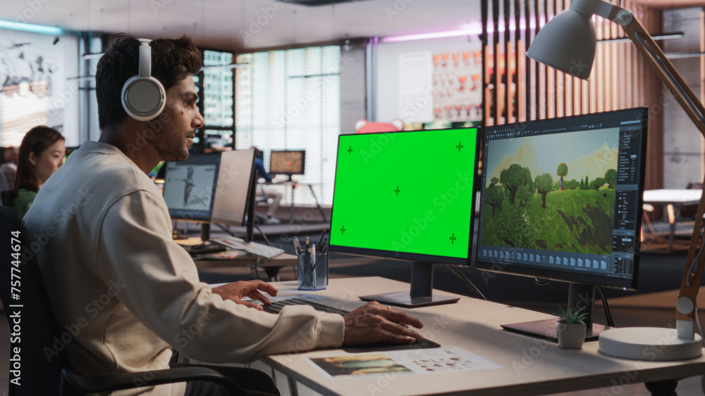 Fototapete Indian Male Game Designer Using Desktop Computer With Green Screen Chromakey on Display, Designing Immersive World In 3D modelling Software For RPG Video Game. Man Working In Game Development Office