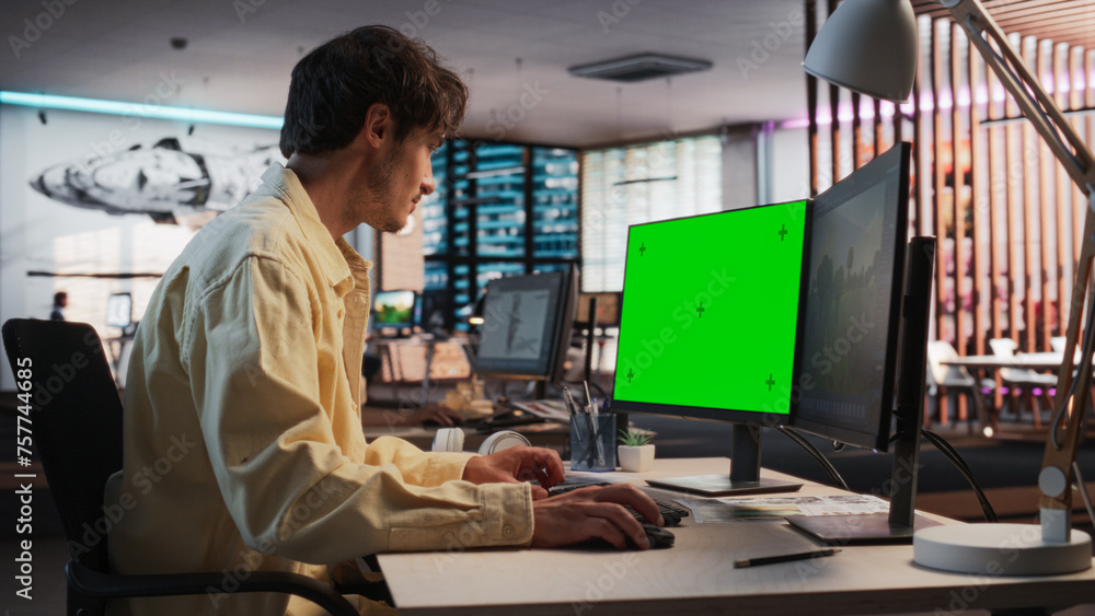 Leinwandbilder portrait of creative caucasian man sitting at a desk using desktop computer with mock-up green scree