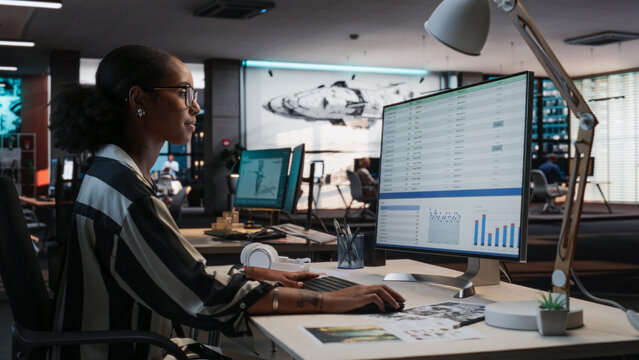 African Female Manager Using Desktop Computer With Analytics Software wth Financial Reports. Woman Working In Game Development Company Diverse Office