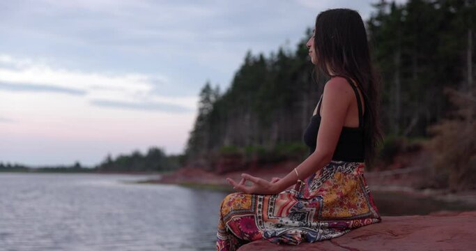 Young woman meditating by ocean  - relaxing calm and peaceful scenery