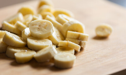 shot of banana slices arranged on a wooden cutting board
