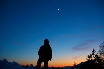 Silhouette of a man walking through the mountains against the backdrop of the night before dawn sky without clouds. Only man and nature. Clean mountain air.