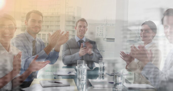 Image of business people smiling and clapping in office over cityscape